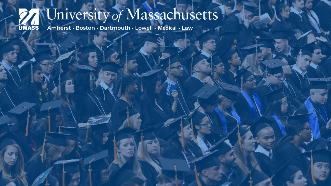 full screen image of students at graduation under a blue transparent overlay with full umass logo in upper left corner