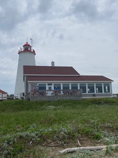 A lighthouse on a hill surrounded by gray clouds.