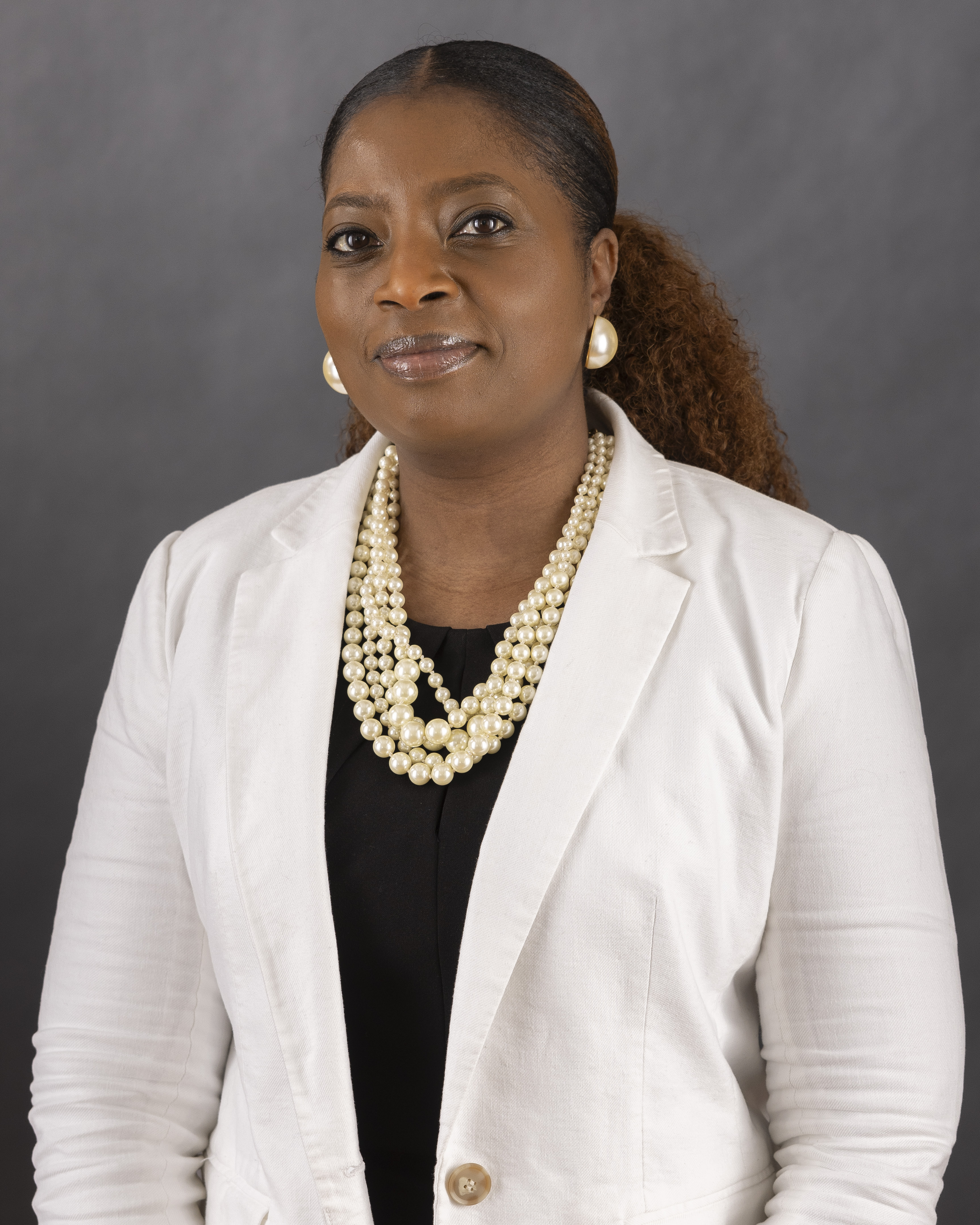 female with white blazer smiling