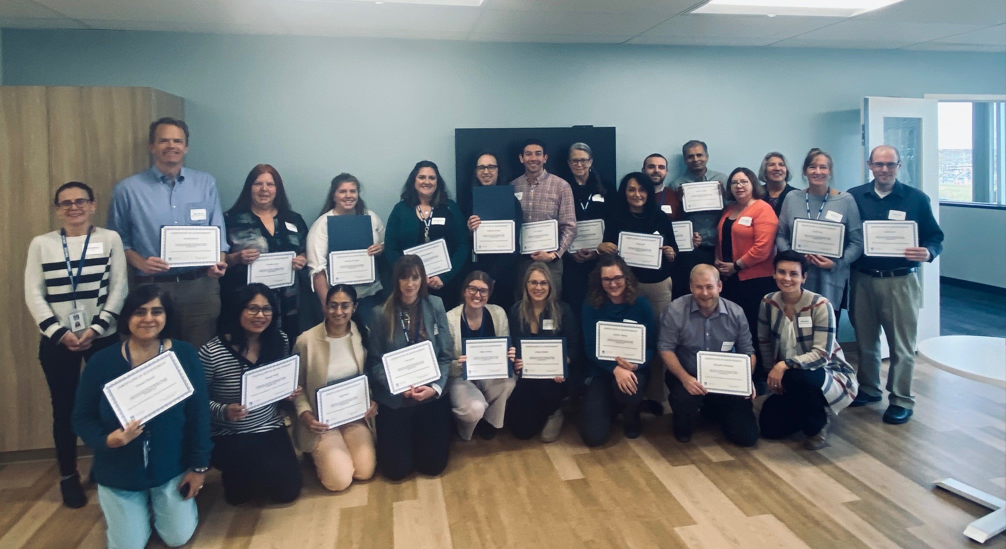 a group of people, men and women, holding certificates and smiling.