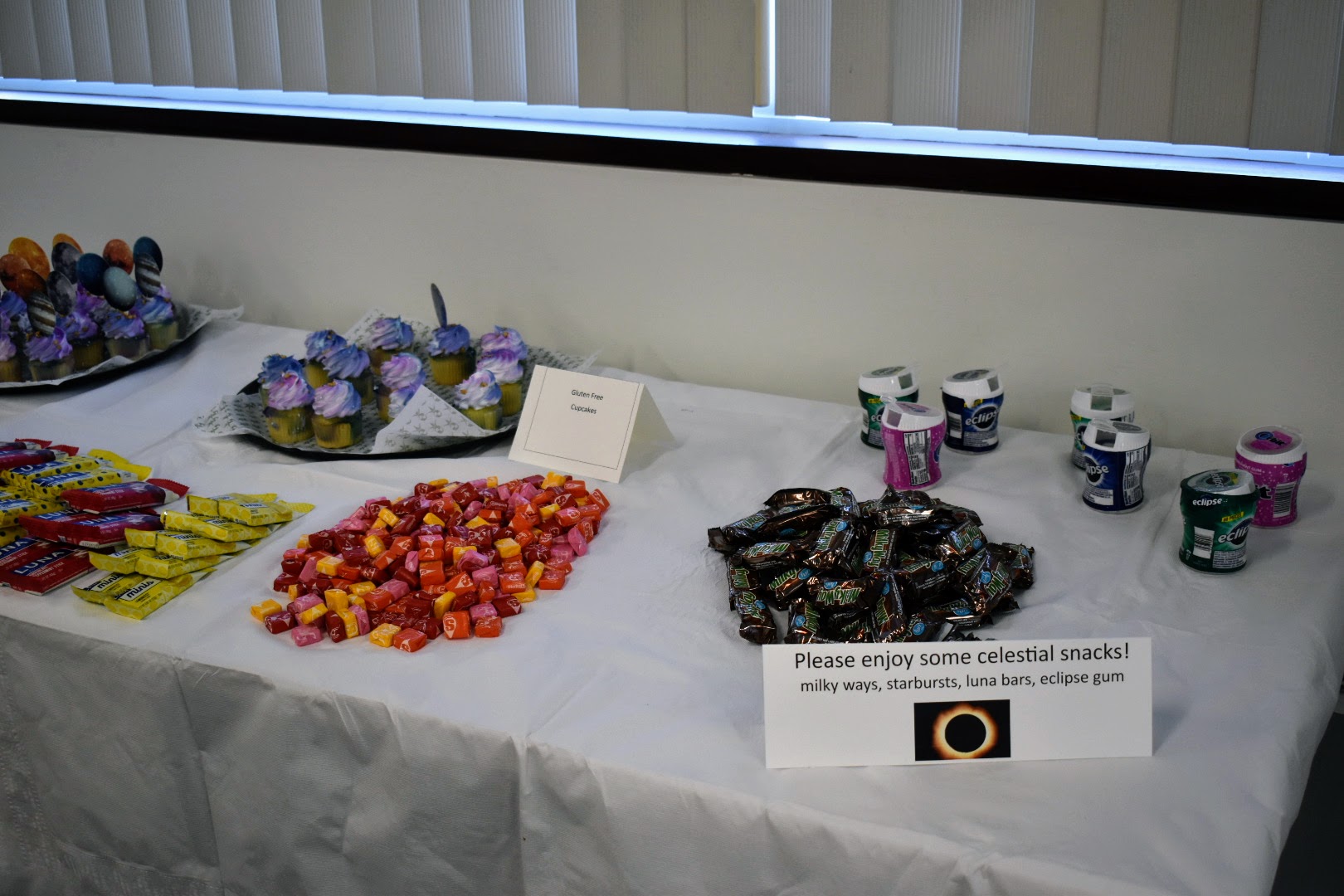 Table with solar eclipse themed candy and cupcakes 