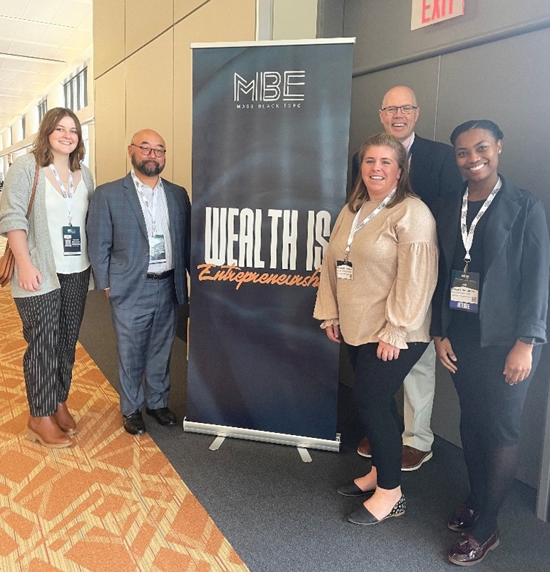 Avery Knott, David Cho, Christine Escobedo, Michael Durkin, and Nakarla Haughton standing in front of a sign