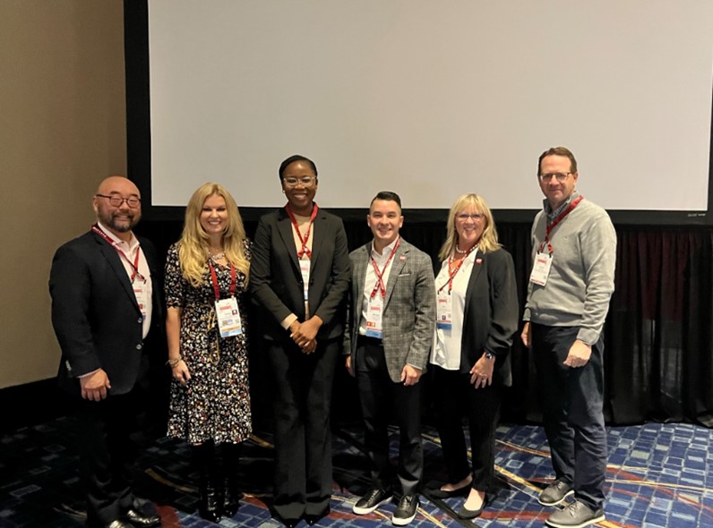 A group of 6 people standing in front of a screen