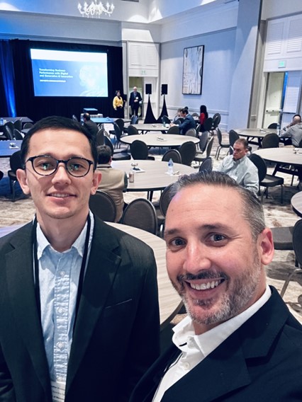 Muzaffar Kosimov and Bill Mannix posing in front of a conference hall