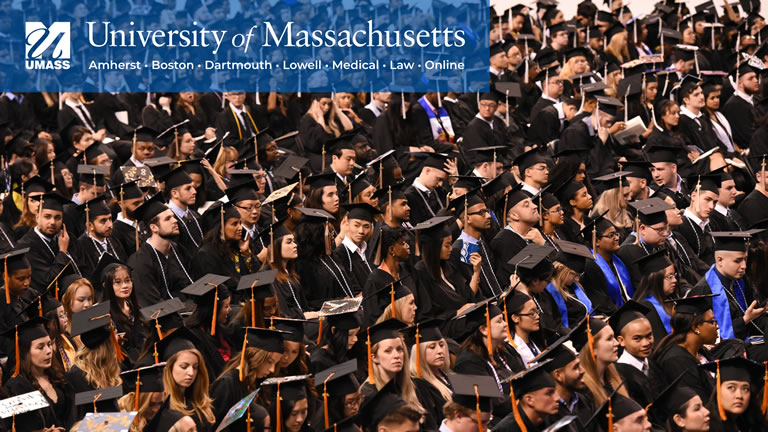 full screen image of students at graduation with full umass logo in upper left corner