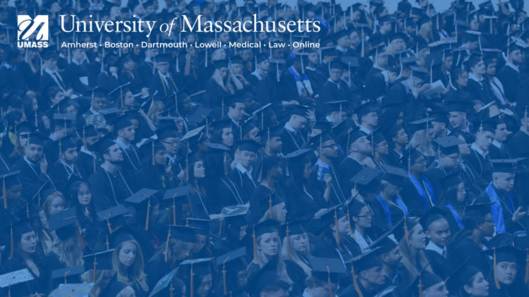 full screen image of students at graduation under a blue transparent overlay with full umass logo in upper left corner
