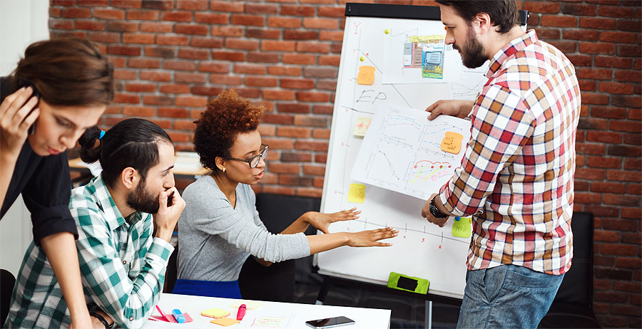 a group of colleagues working around a white board