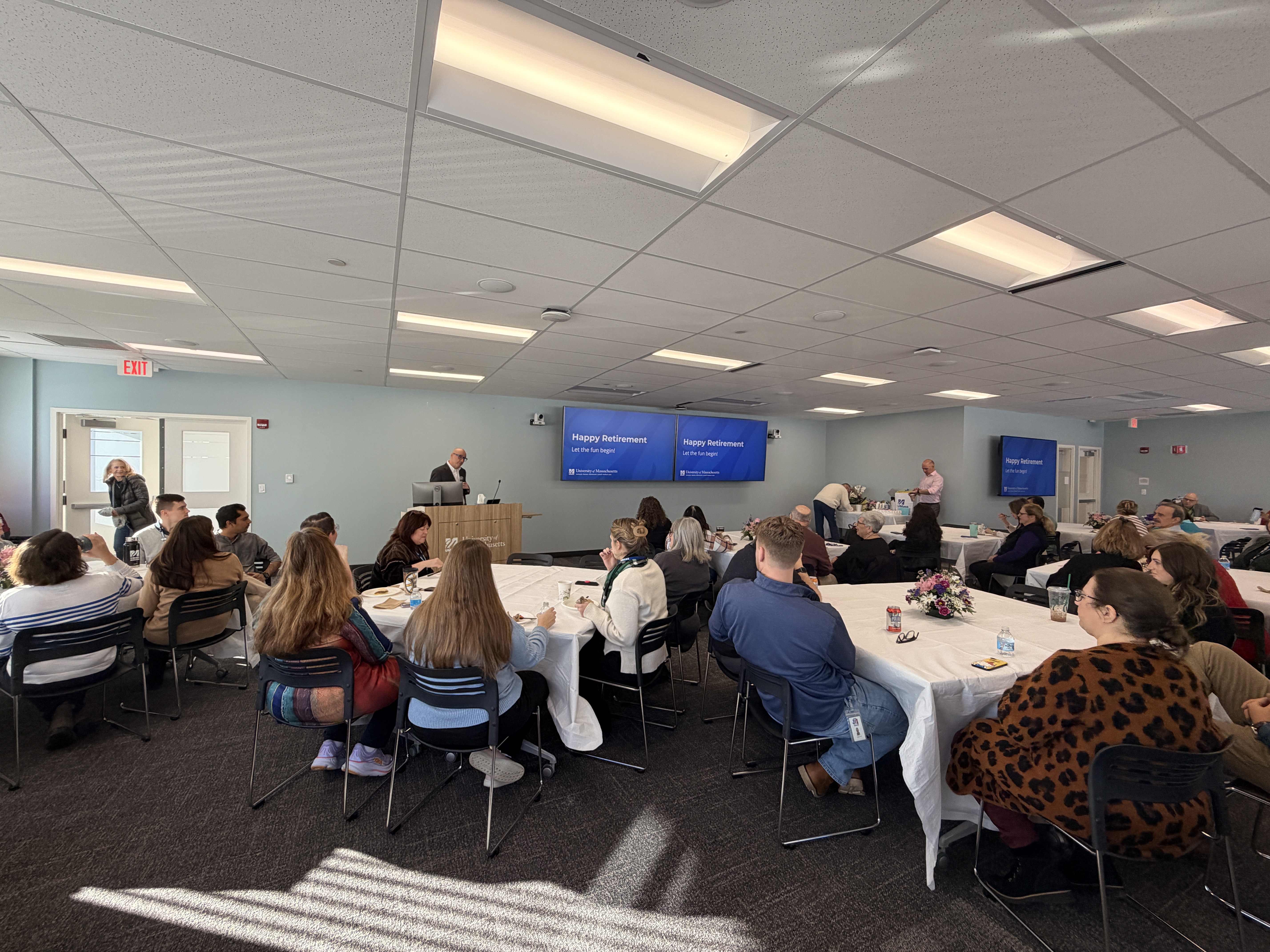 John Dunlap presenting behind a podium to a large group of seated people