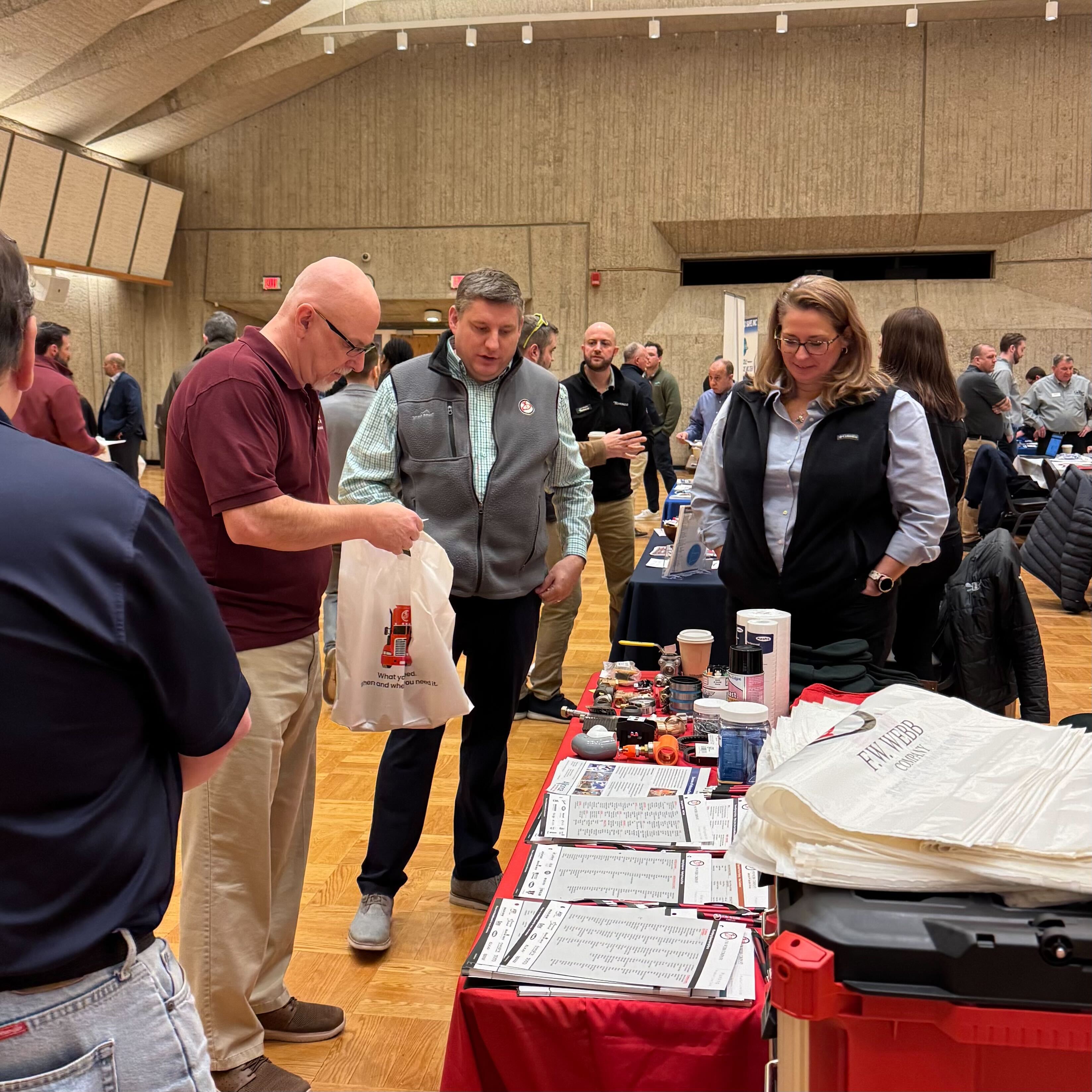 Two men and a woman gathered around a waist height table looking at papers and little souvenirs