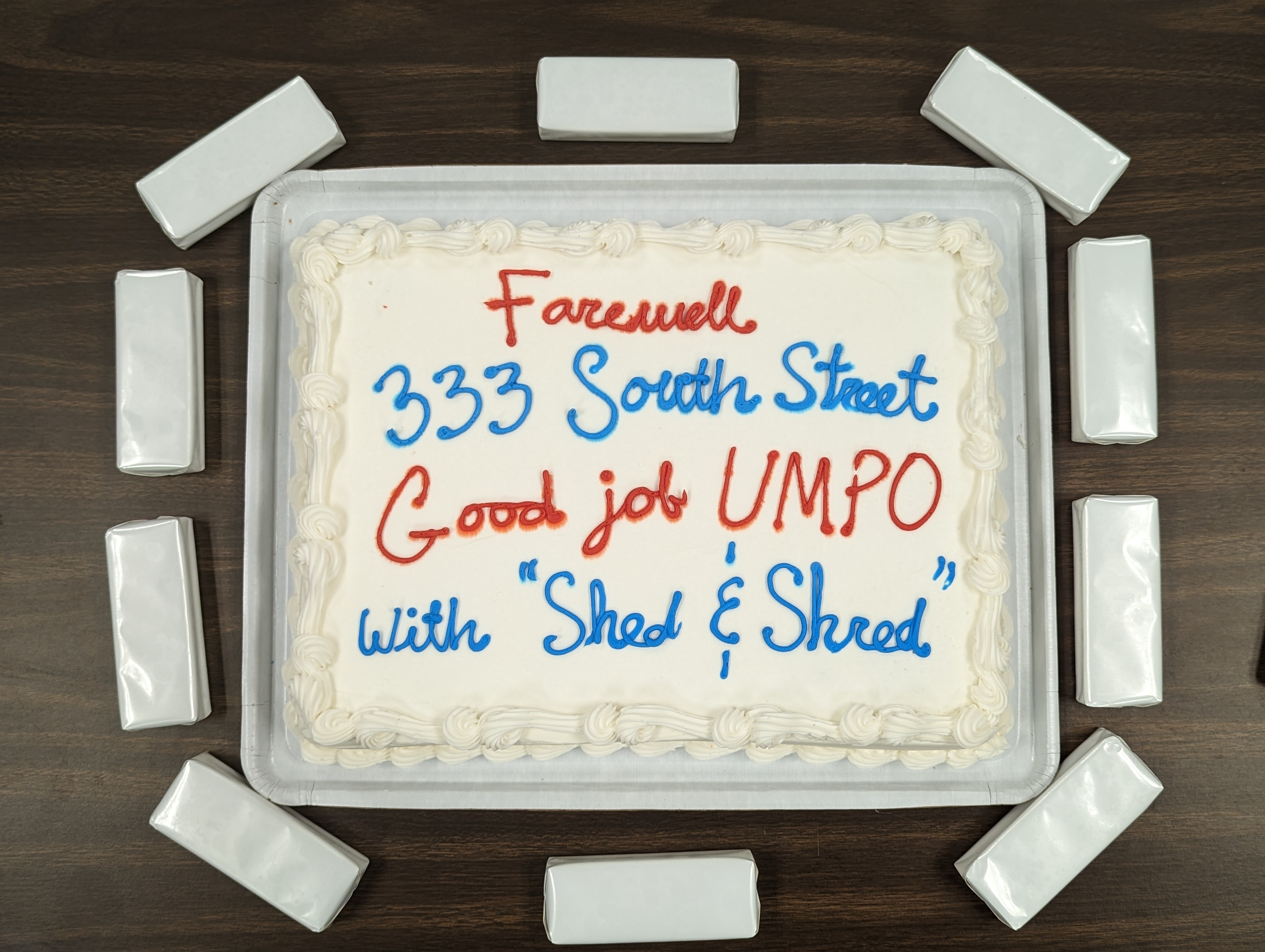 A white cake with "Farewell 333 South Street Good job UMPO with "Shed & Shred"" written in red and blue icing