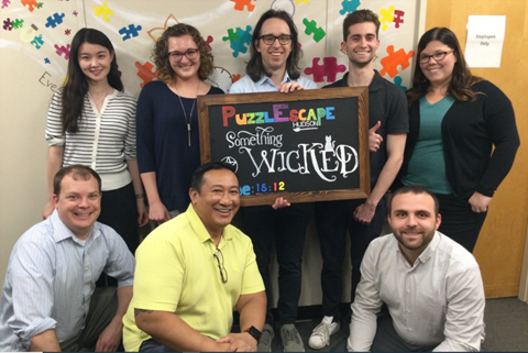 8 people holding a sign and smiling