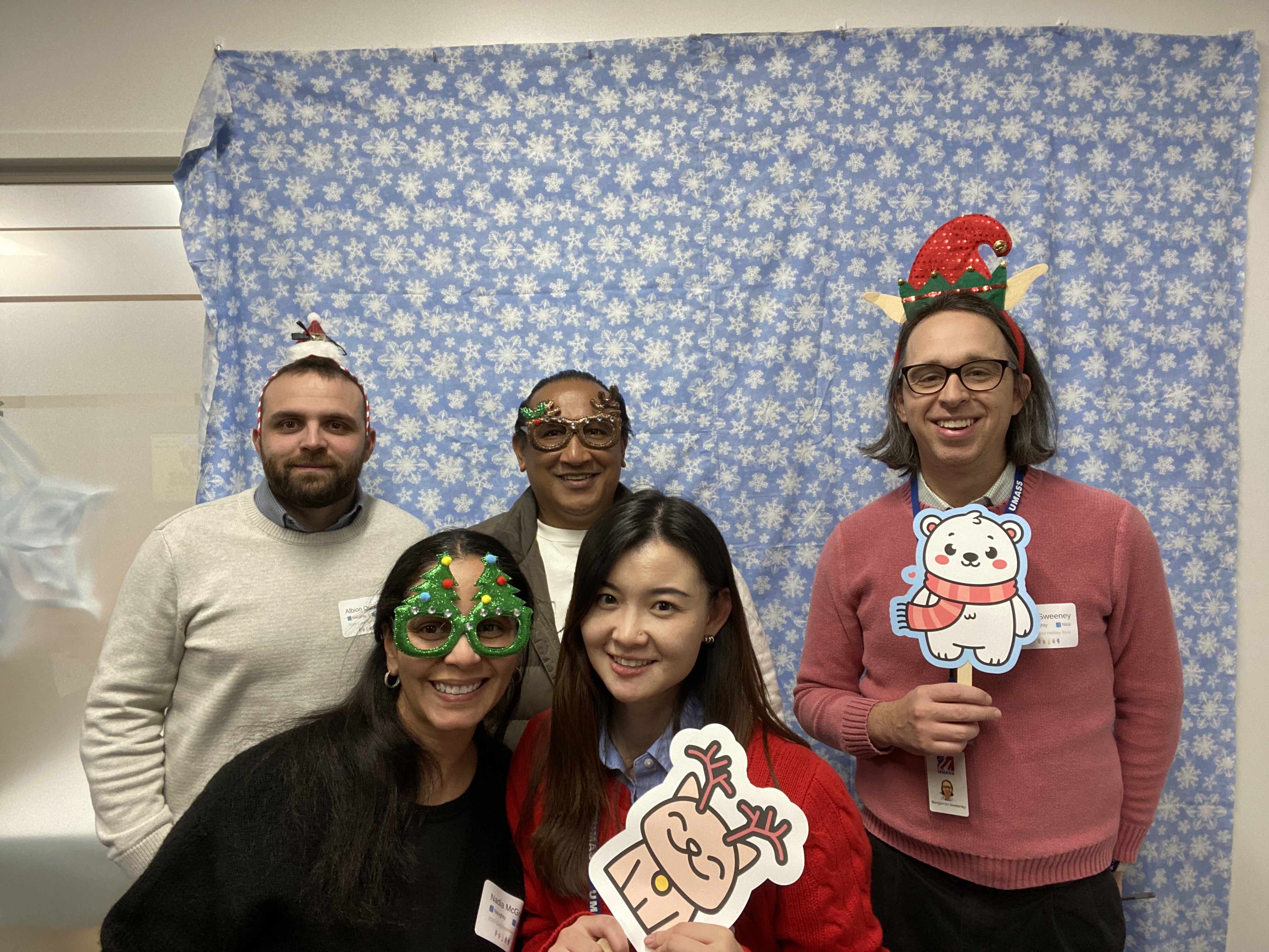 A group of coworkers with holiday hats on smiling at party
