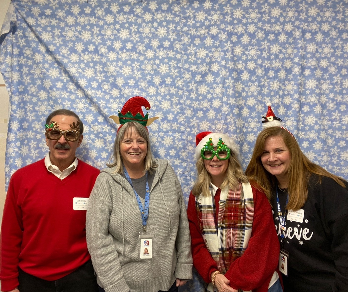 A man with 3 woman smiling dressed in holiday clothes