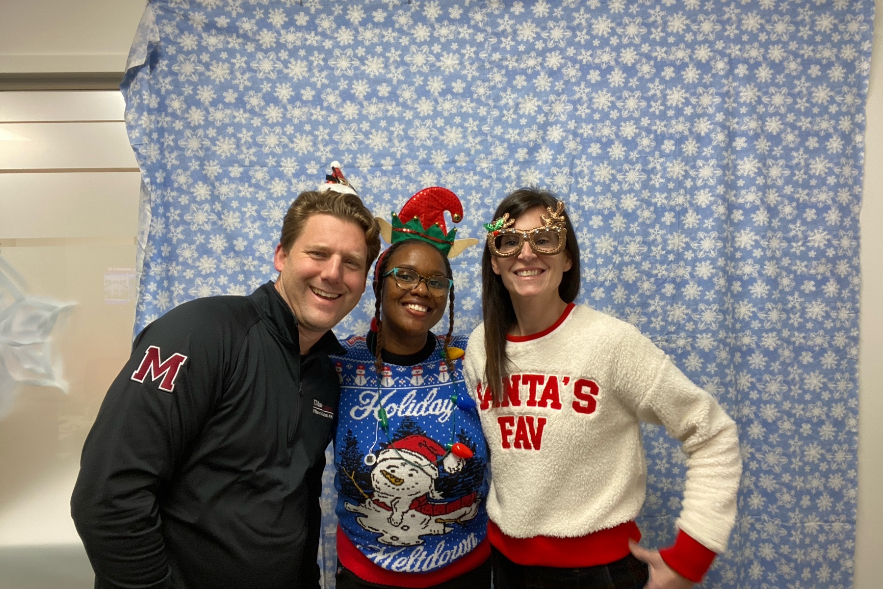 A male colleague with 2 woment posing for a picture in holiday clothes