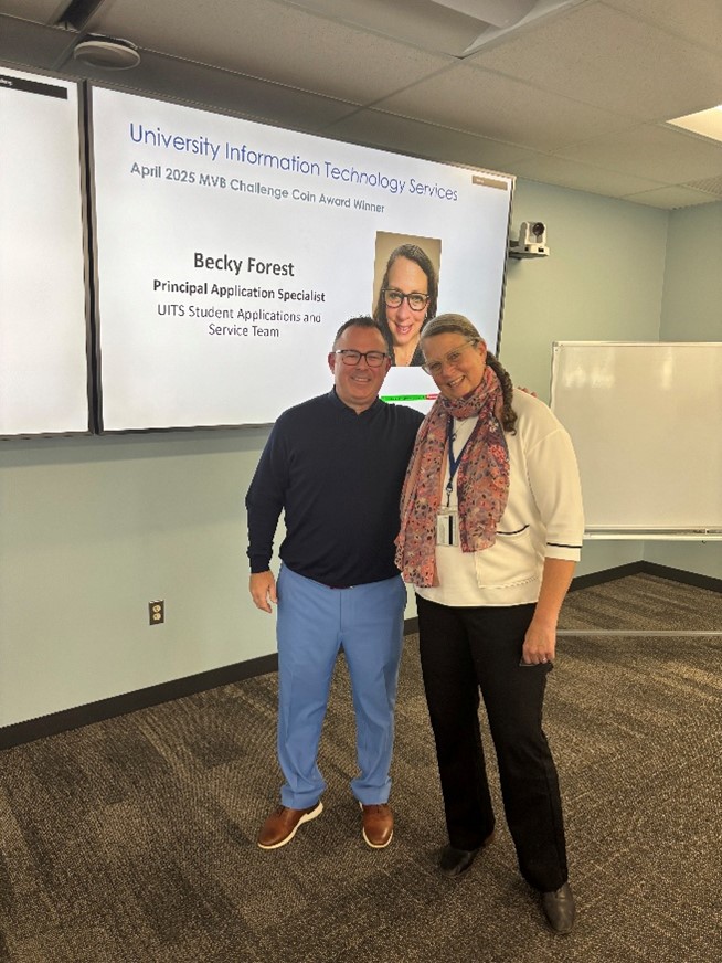 Michael Milligan and Becky Forest standing in front of a screen