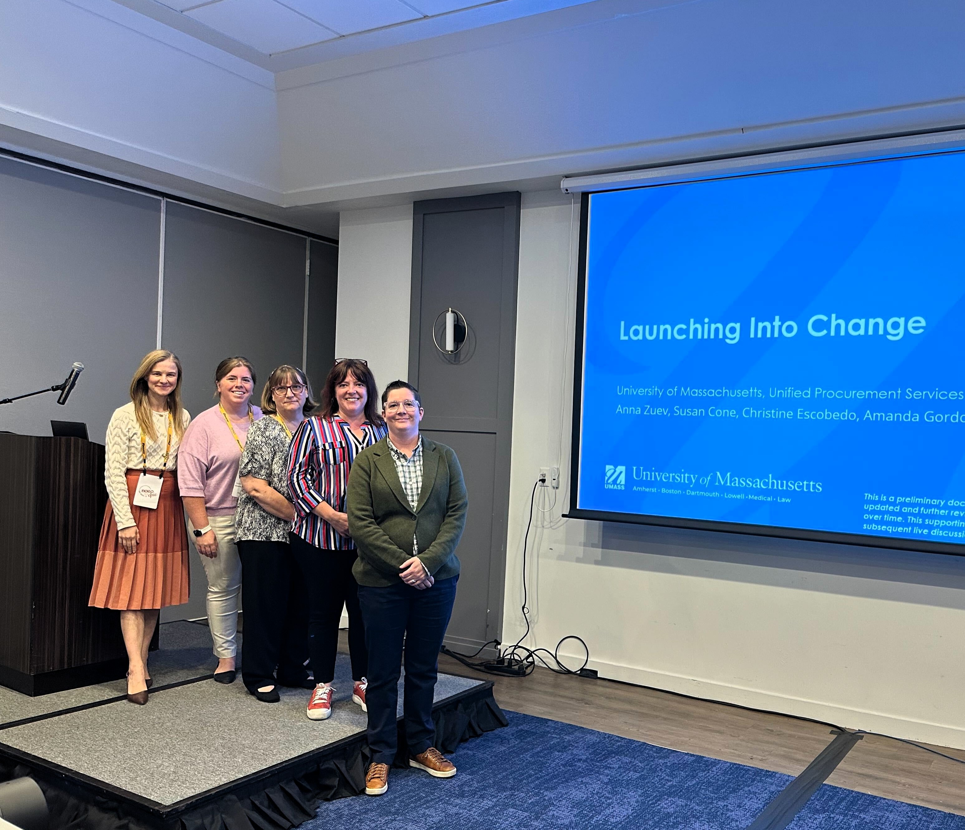Four members of UPST posing in front of a blue powerpoint that says Launching into Change