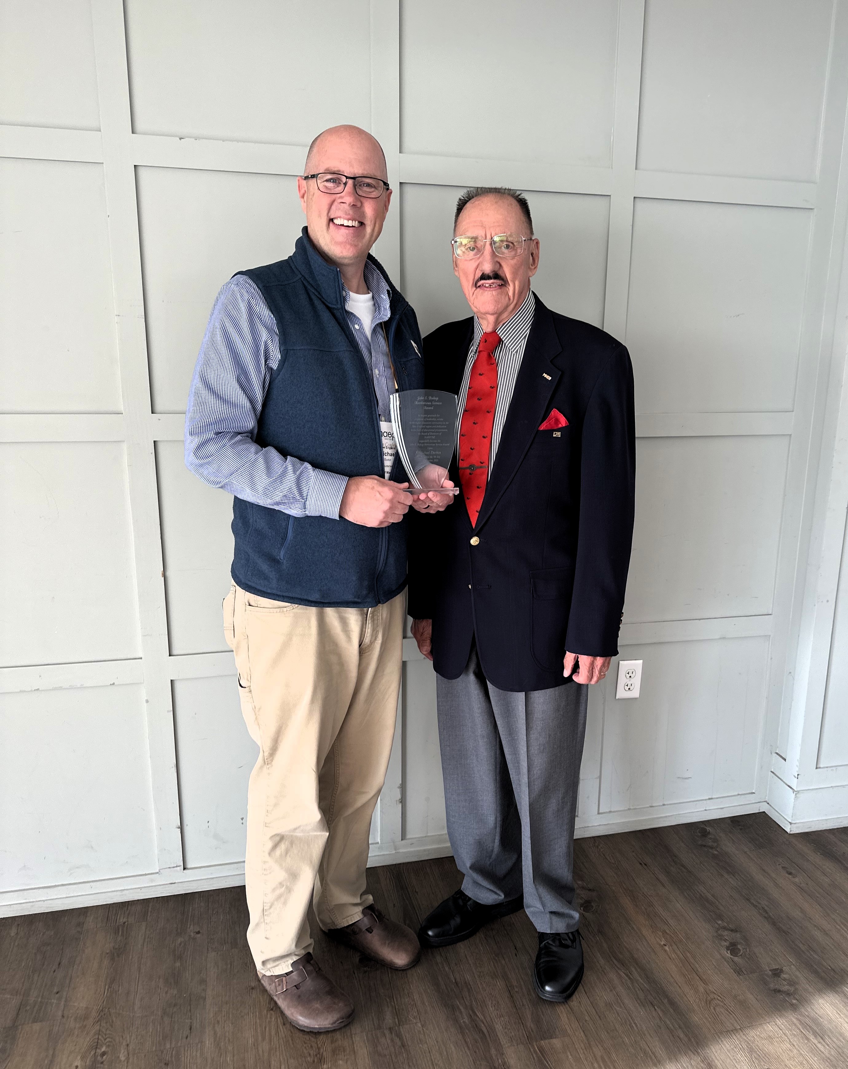 Michael Durkin holding the Jake E. Bishop Meritorious Service Award with another conference attendee