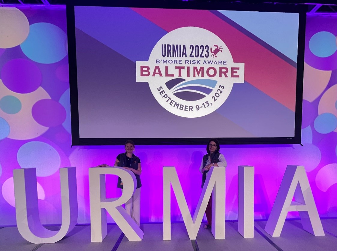 two women standing in front of a large screen