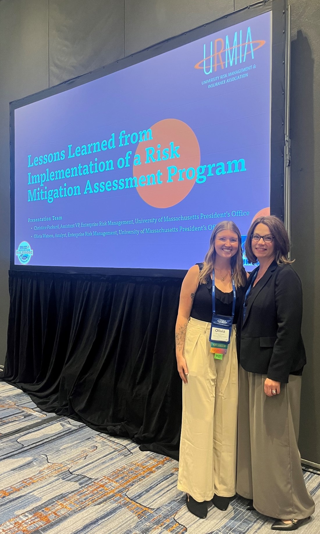 two women standing in front of a large screen