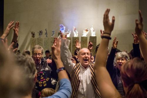 People dancing with arms in the air during Hanukkah celebration in the MFA Shapiro Family Courtyard