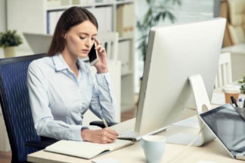 professionally dressed employee at a desk writing notes