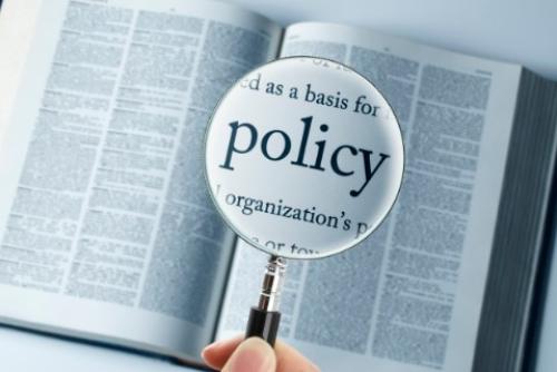 open book with magnifying glass over the word 'policy'