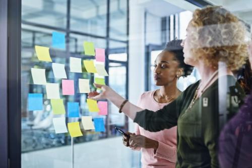 two people looking at sticky notes on a glass