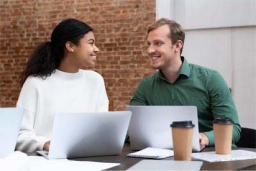 Dark-skinned woman meets with light-skinned man in a corporate setting.