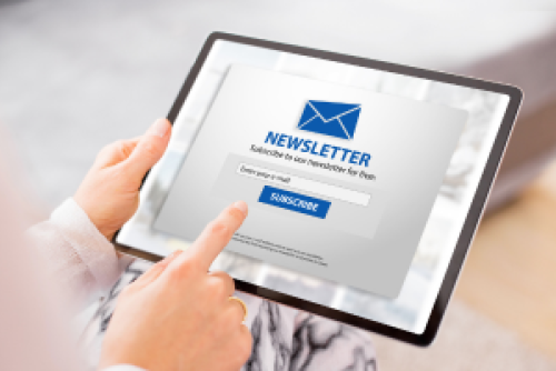 woman holding a tablet with an email newsletter showing on screen