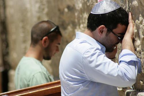 A Jewish man leans against the prayer wall.
