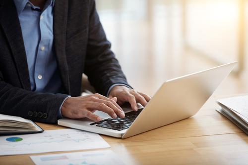 A man with medium-light skin types on a laptop.