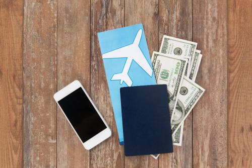 a cell phone, passport, airline ticket and cash arranged on a table