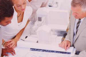 "Two men and two women looking at plans on paper."