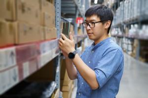 asian man in supply warehouse looking at his phone