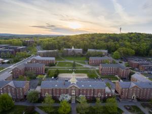 "Brick campus buildings with a sunset and forest in back."