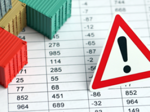 Close up of sheet of paper with a data table of numbers and a caution sign with small toy storage containers on top