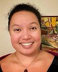 Student Trustee Bethany Berry is smiling, wearing a burgundy color blouse and an oval-shaped pendant, standing in front of artwork