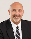 Kenneth Fiola Jr in a dark suit with a white business shirt and black and gray diagonal stripes necktie