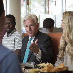 President Meehan sits at a table talking to students.