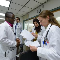 Research students wearing lab coats work in a group in a classroom.