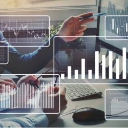 graphs overlayed on hand pointing at computer monitor