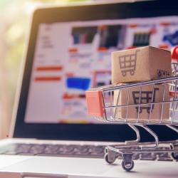 mini shopping cart with boxes in front of laptop