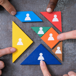 Picture of triangular puzzle pieces with person icons on them being pushed together by 5 point fingers