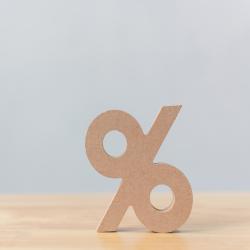 A wooden percentage sign block sits on a wooden table.
