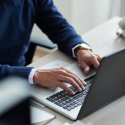 A man's hands type on a laptop keyboard.
